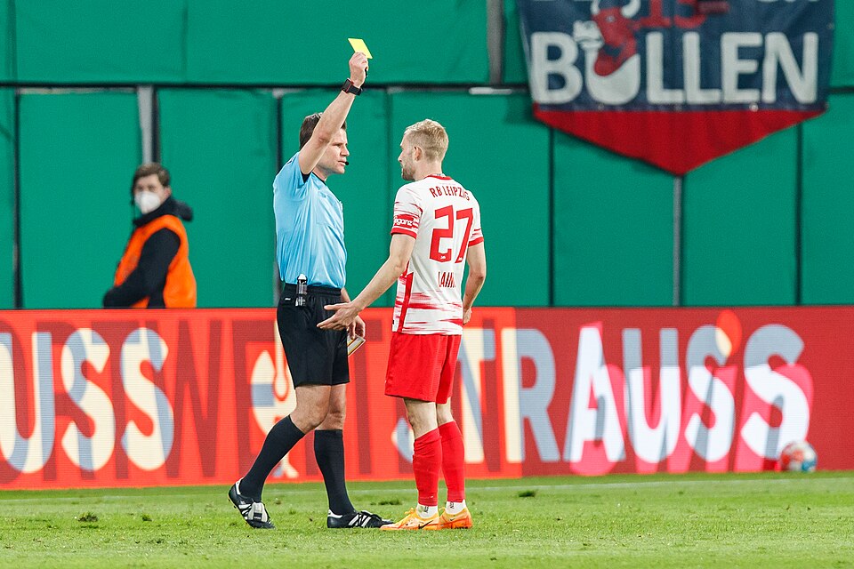 Árbitro mostrando tarjeta amarilla a un jugador durante un partido intenso