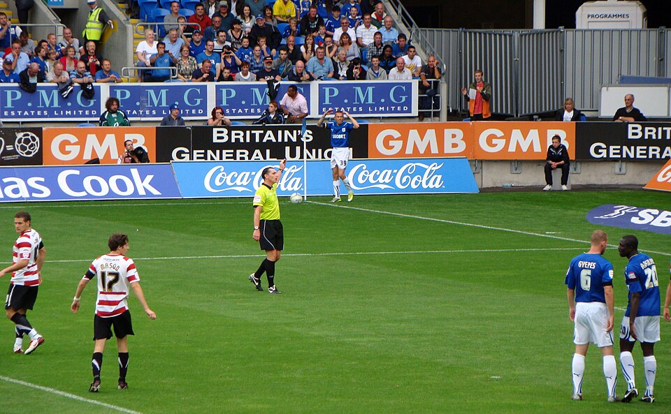 Árbitro mostrando tarjeta amarilla en un partido de fútbol